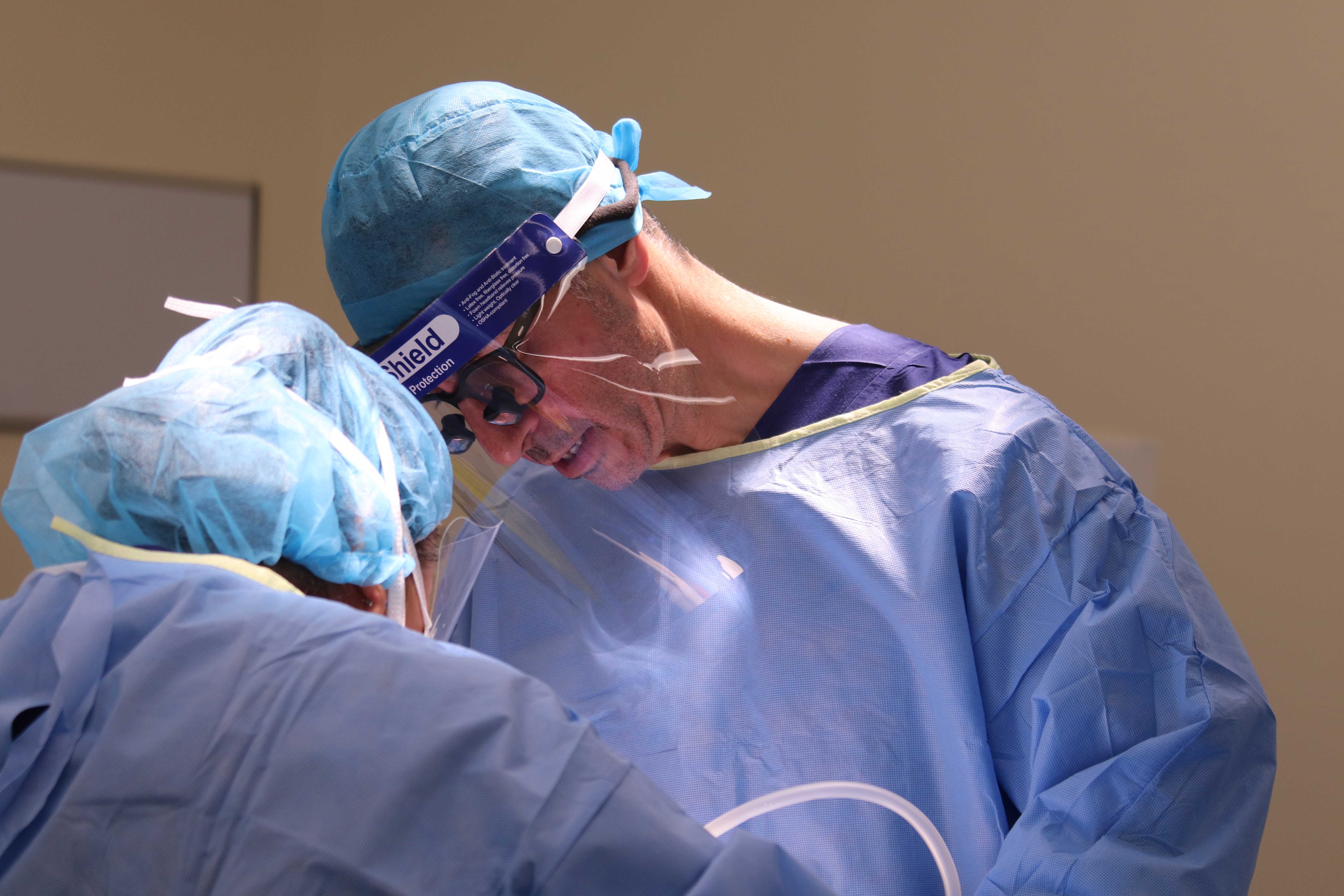 Mohs Surgery Sydney image of Dr Anthony Maloof, operating on a patient. Deep concentration can be seen through the visor. Loops are worn to zoom in on the surgery.